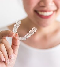 smiling person holding Invisalign tray 