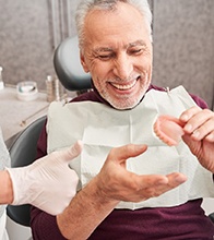 Older man holding dentures in Blaine