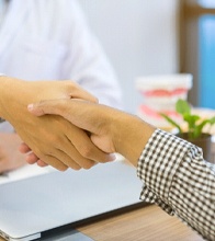 Dentist and patient at a desk shaking hands