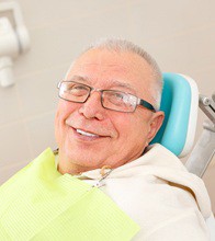 Older man smiling while visiting an implant dentist in Blaine