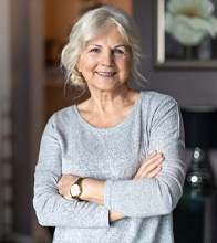 An older woman smiling with her arms folded