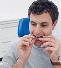 Invisalign patient putting aligner in his mouth