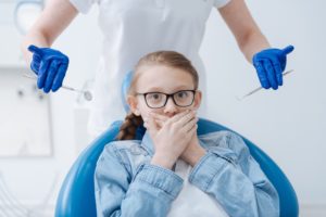 fearful child covering mouth at dentist