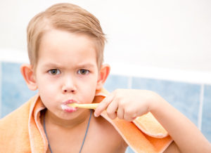 blonde haired boy brushing teeth