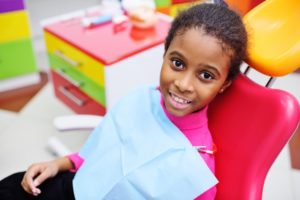 a young girl sitting in the dentist chair smiling