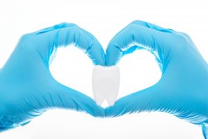 hands forming heart around tooth