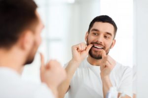 man flossing to maintain oral hygiene during COVID-19