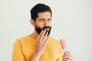Pained man with popsicle hand to cheek should see Blaine dentist