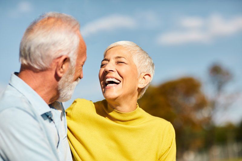 an older couple laughing and smiling while enjoying the outdoors