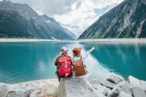 A couple sitting on a rock overlooking a lake and mountains