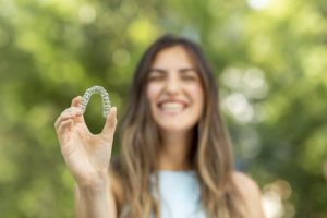 smiling woman holding Invisalign 