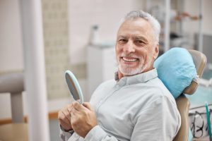 senior man smiling while visiting his mercury-safe dentist 