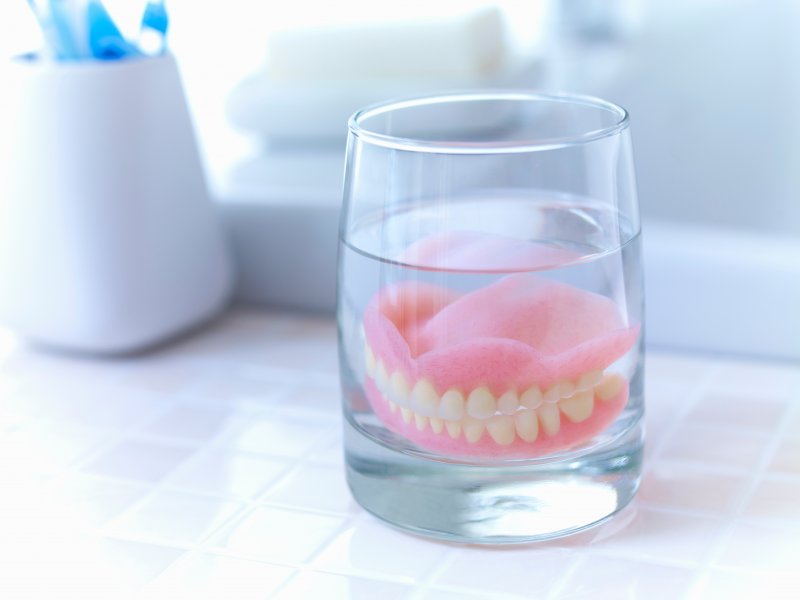 A set of dentures soaking in a cleaning solution